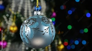 Rotation of a blue Christmas ball and decorated Christmas tree, against the background of a blinking garland.