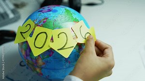 Future Planning with 2026 on Globe, Hand places sticky notes with 2026 on a globe, symbolizing future planning