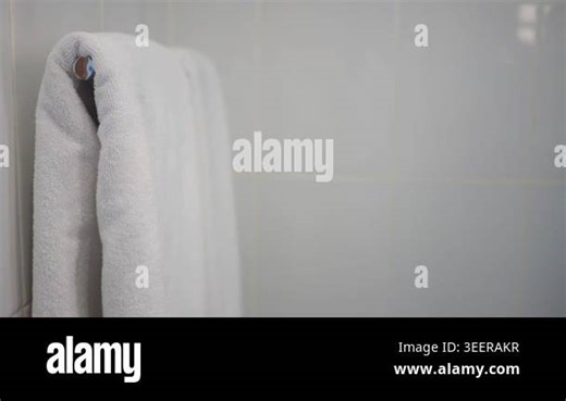 A white towel hangs on a rack in a bathroom. The wall is tiled Stock Video Footage - Alamy