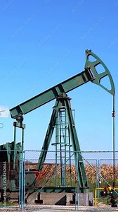 Oil Industry Pumpjack Extracting Crude Oil from a Oil Well. Fossil Fuel Energy. Oil Industry Equipment. Oil Field Pump Jack Against Blue Sky.