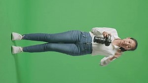 Full Body Of Angry Asian Photographer Using A Camera Taking Pictures Then Shouting To Someone While Standing On Green Screen Background In The Studio