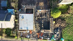 Aerial footage of the UK village of Wetherby in Yorkshire showing building work being done on a new house roof and a construction site on a housing estate from above