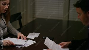 A husband and wife looking over bills, fighting and looking stressed