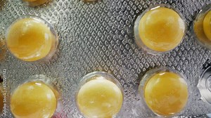 CU, macro, dolly cam: new silver blister with bright color yellow dragees using to cure symptoms and dangerous disease at light extreme close view