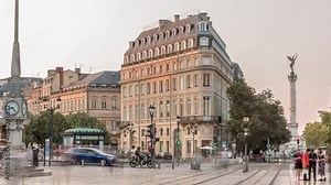 Triangular building and modern tram at Place de la Comedie timelapse, Bordeaux, France, during sunset. Shadow move across the facade and a streetlight with a clock adds elegance to this urban landmark Видео Stock