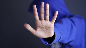 Download A person in a blue hoodie is making a stop sign for free