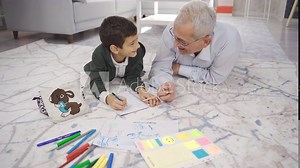 Father helps his son with his homework. Father and son draw pictures and do homework at home.
