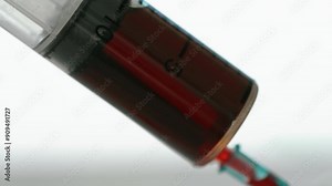 A syringe filled with red liquid is being used to inject a patient