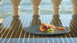 The chief cook decorates a dish of high cuisine with the help of tongs. Dishes at the gourmet restaurant. Close-up. Cutlet from rabbit meat with a garnish of green buckwheat