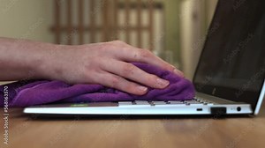 Cleaning, wiping laptop keyboard from dust, dirt, surface clean. Hand with cloth on computer keyboard closeup. Technology hygiene maintenance