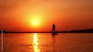 Sup boarding on the river in summer. Male silhouette floats on water standing on sup board and rowing with a paddle.