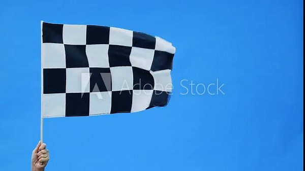 Human hand waving checkered flag on blue sky background, slow motion video