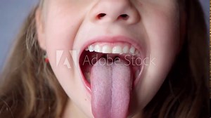 girl opens her mouth wide and pulls out long tongue. child shows his teeth soft palate and mouth to dentist. mouth is wide open, tongue is stuck out as far as possible, with clear view of tongue