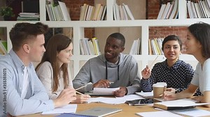 Happy multiethnic diverse college university students team study together prepare for exam in library, multicultural young people group talk laugh help do research project brainstorm in cooperation