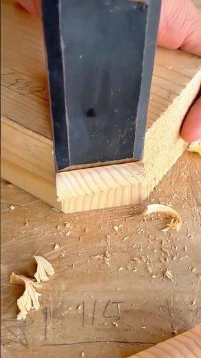 Woodworker using a wide chisel to clean and define a rabbet or dado joint in wood
