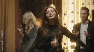 drunk young woman with wine glass in hand dancing cheerfully on dance floor of bar or restaurant