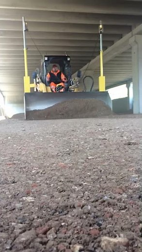 Skid steer CAT 277 grading an industrial building