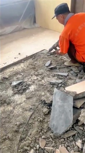 Worker removing old ceramic floor tiles using electric chisel