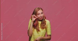 Little bit gesture. Funny happy young girl showing small size by fingers, winking ask little more, body language concept
