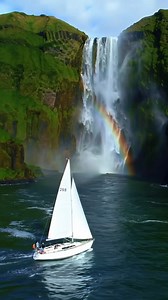 ⛵🌈💦 "Sailing through nature’s magic — waterfalls, rainbows, and the ocean’s embrace." A sailboat glides past a roaring coastal waterfall, misty spray and a rainbow painting a dream on the sea. #WaterfallSailing #RainbowMist #NatureWonder #CoastalAdventure #SailingMagic #OceanDream #LushCliffs #EpicSail | Love Sailing