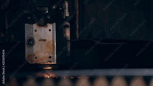 Programmed robot head cuts a huge sheet of metal. Robotic CNC laser plasma cutter cuts metal parts with great precision. Modern industrial technology. Bright sparks light. Machine at work. Close up.