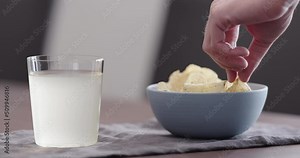 Slow motion man take potato chips with ground pepper and salt and drink ginger beer