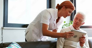 Nurse and senior patient using tablet computer in retirement home