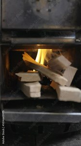 Fire burning with logs in a small rocket stove with beautiful yellow flames. Handheld vertical video