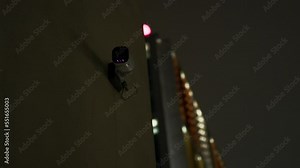DARK view over a CCTV camera against a modern building at night