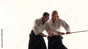 Two athletes performing aikido using bokken. Isolated, white. Close up. Slow motion.