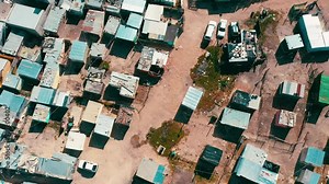 Poor, neighborhood and houses in community from drone with village, dirt road and landscape of South Africa. Township, location and rooftop of shack property, settlement or homes on street in ghetto