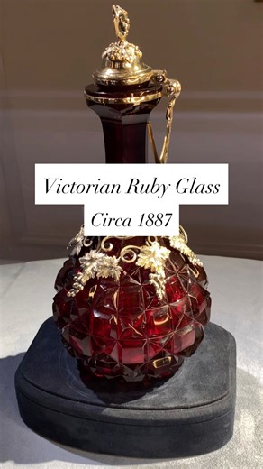 This exquisite ruby glass jug by Elkington & Co. is mounted with gilt silver in a finely detailed grapevine motif, signaling its intended use as a wine decanter. The vibrant red glass is precisely cut to exceptional caliber, while the silver mounts are intricately rendered, with broad leaves, twisting vines and clusters of grapes applied to both the body and lid. The rich cranberry coloration is achieved through the addition of gold to the molten glass, a process that made ruby glass items such 