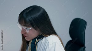 Beautiful young woman with long dark hair wearing glasses answering a phone with a client close up in slow motion. Secretary working hard in office.