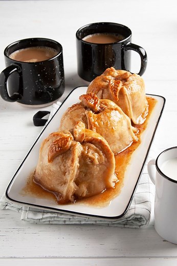 "This warm and comforting apple dumplings recipe is incredible by itself or served with ice cream. You can decorate each dumpling by cutting 1-inch leaves and a 1/2-inch stem from the leftover dough." —Robin Lendon, Cincinnati, Ohio. Get the recipe for Apple Dumplings with Sauce: https://trib.al/zYRqeqo | Taste of Home