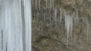 CLOSE UP: Enormous icicles hang from an overhang in a narrow Mostnica Gorge. Beautiful ice formations created by the freezing of trickling water. Wonderful creations of nature in cold winter season.