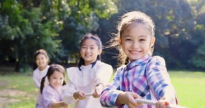 Happy Children playing tug of war at the park