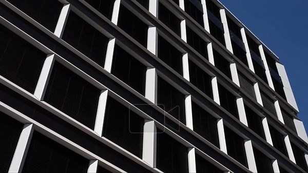 Close-up perspective of a contemporary business building exterior featuring a repetitive grid pattern of white frames and dark windows. The shot highlights the clean lines and geometric design of modern urban architecture Stock Video Footage - Alamy