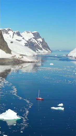 Vertical video landscape of Antarctic Ocean with snowy mountains, ice and ship.
