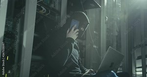Hacker in black mask with laptop talking smartphone stops cyberattack and runs away. Cyberattack and data security concept.