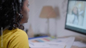 Close up of face and hands of young concentrated African American girl working with drawing tablet computer. Self-taught woman practicing from home office at desk. Enterprising people of generation z.