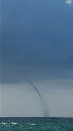 Dramatic Waterspout Swirls over Ocean from Beach
