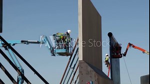 Low angle of two men in a telehandler working in The Trump's Wall
