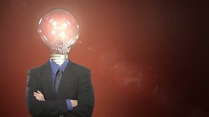 A man in a suit with a light bulb in place of a head steps into frame, taps the bulb, and a light flickers on. Centered version also available.