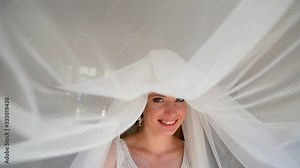 Adorable young bride is getting ready in the morning at home. The bride getting ready for the wedding is dressed in a white dress