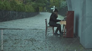 Girl playing the piano outdoors on a rainy day
