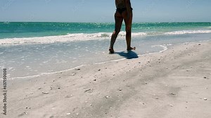 Beautiful woman in bikini walking on tropical sandy beach