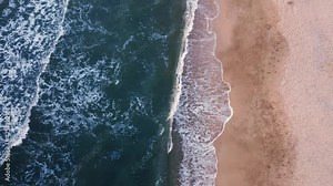Beautiful sandy beach and foaming waves on the ocean or sea. View from above.