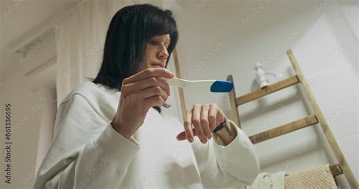 Woman checking result in restroom, waiting result of pregnancy kit test for motherhood. Pregnancy test kit in hands