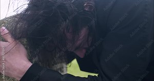 Distraught, emotional, crying man grieving the death of loved one in cemetery.