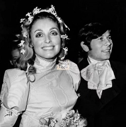 "On their wedding day, circa March 20, 1968, Sharon Tate and Roman Polanski were photographed beneath the gray London sky as they emerged from the Chelsea Registry Office, newly married and radiating the aura of a modern, cinematic couple on the rise. Tate, 25, wore an ivory moiré silk minidress with a Peter Pan collar designed by Ozzy Clark, paired with white tights and delicate heels—a striking symbol of 1960s fashion rebellion. Polanski, then 34 and flush from directing Repulsion and Cul-de-S